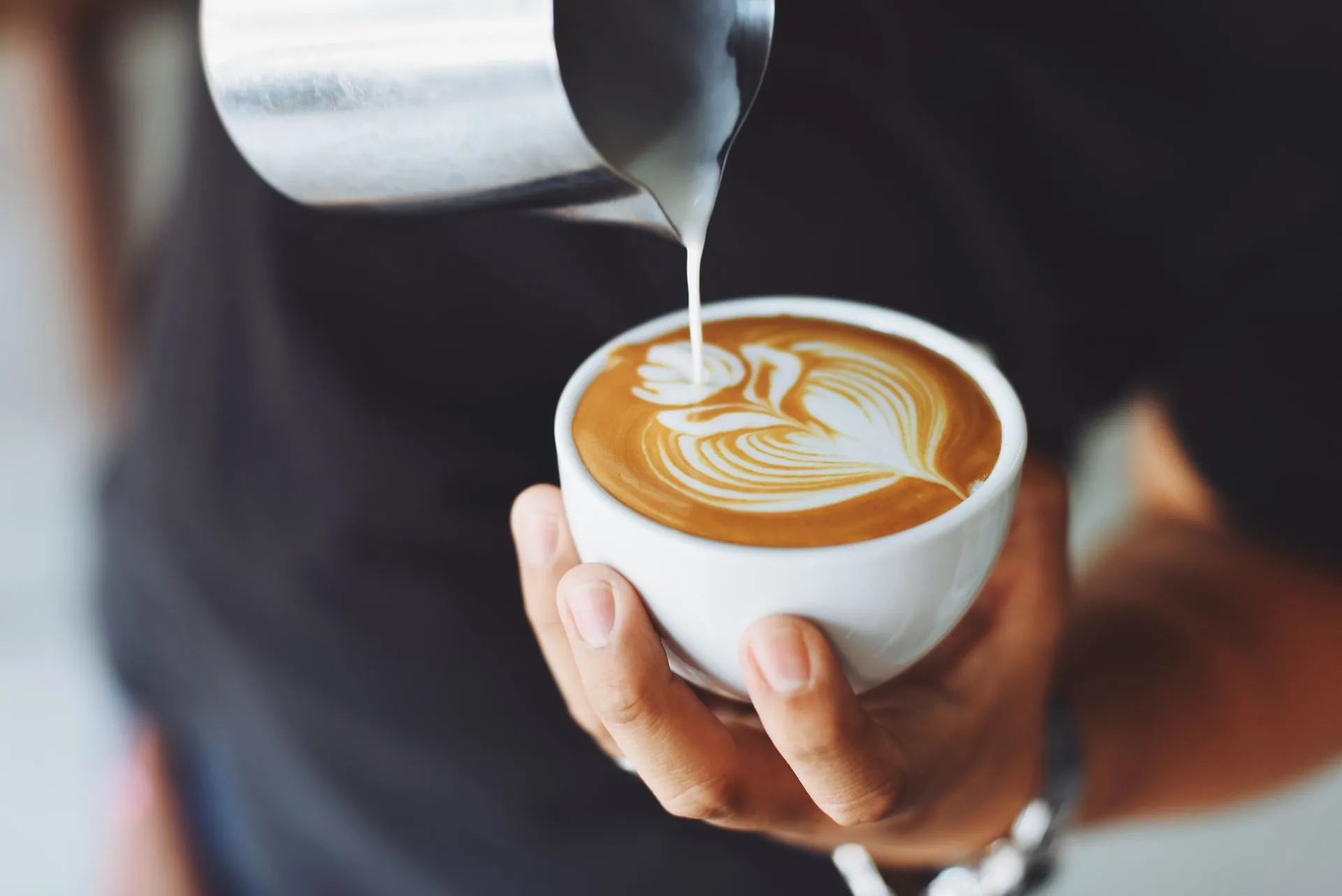 Barista pouring steamed milk into a latte at Ember & Oak